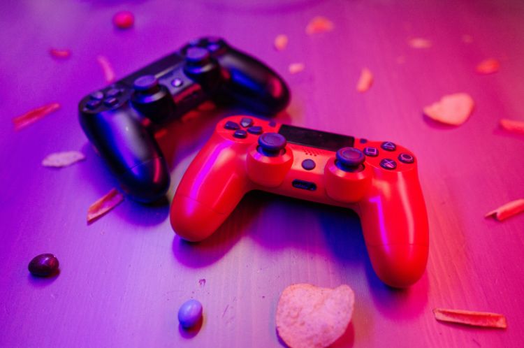 Imagine of a black and a red PS controller with individual snack items placed around them as if confetti