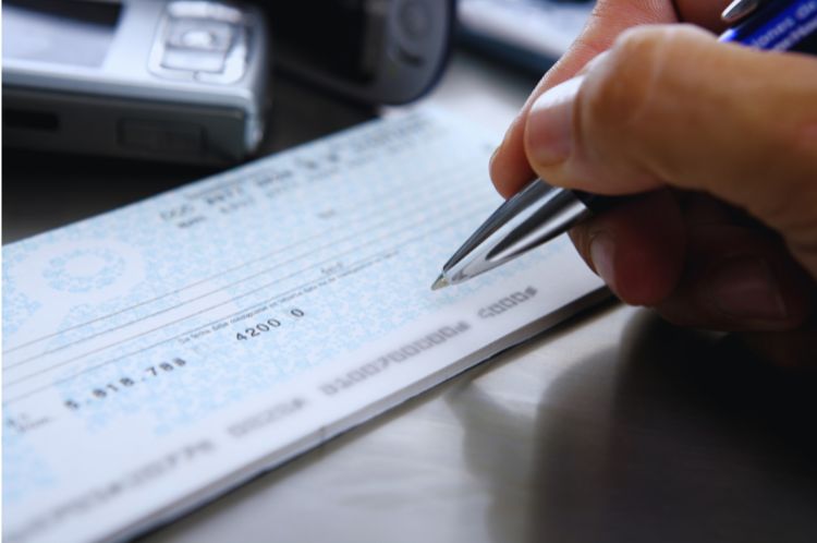 a close up of a hand writing a cheque