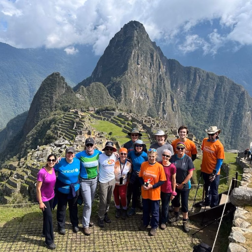 A group of trekkers stand in front of Machu Picchu